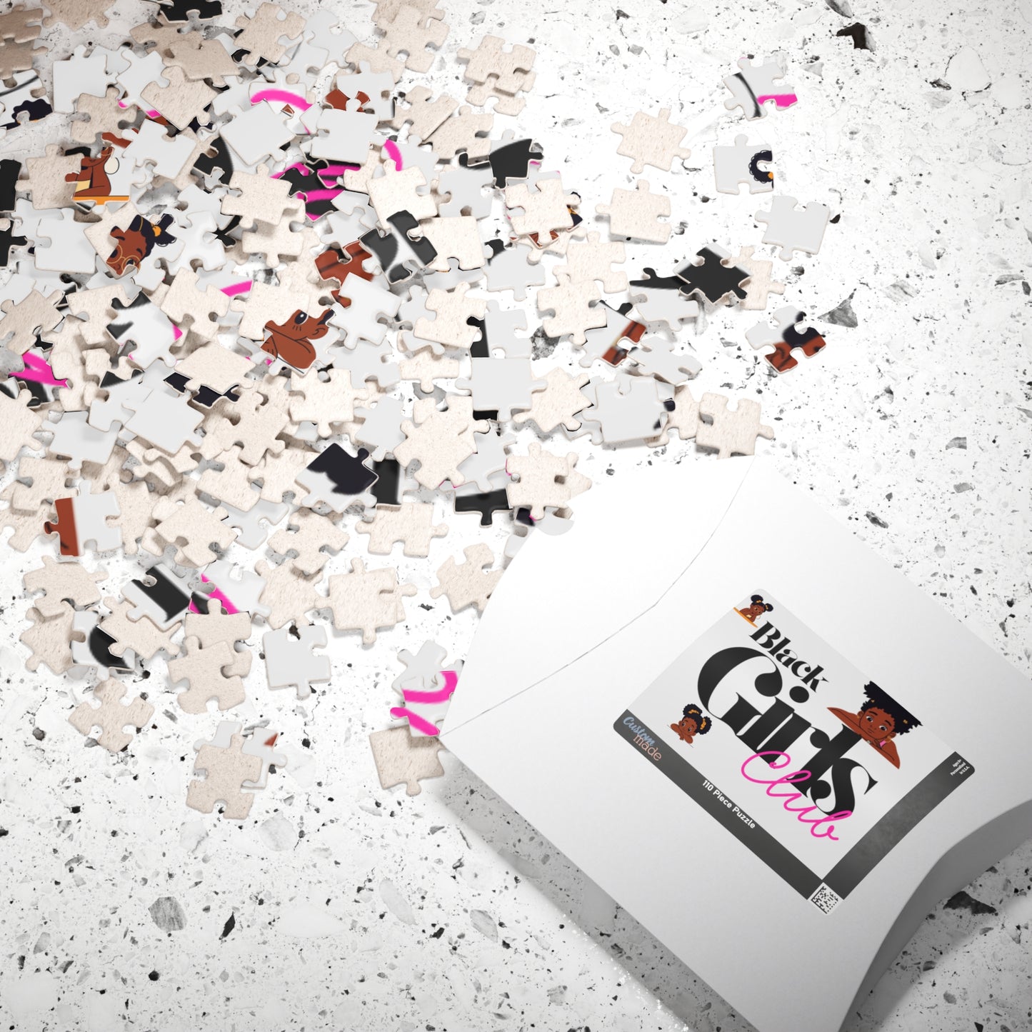 Pile of puzzle pieces with a box labeled 'Black Girls Climb' on a speckled surface.