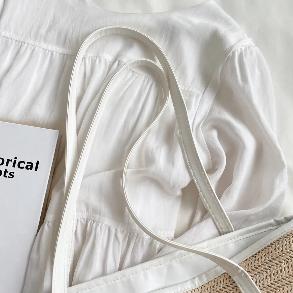 Large white straw bag laying down on white cloth.