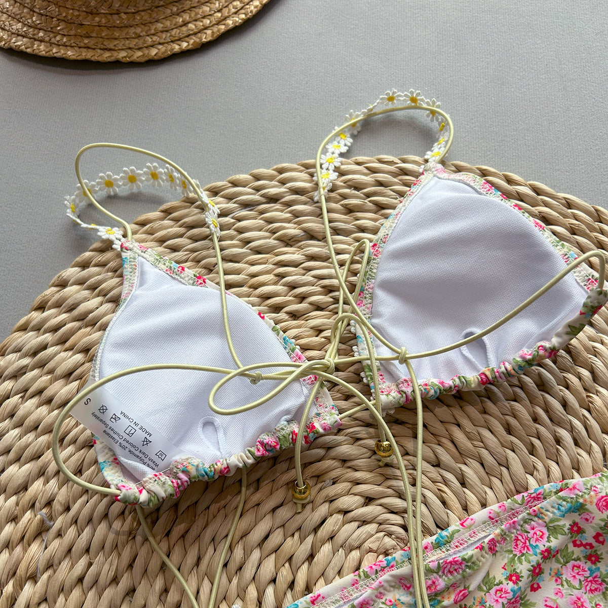 White bikini top with floral trim on a woven mat