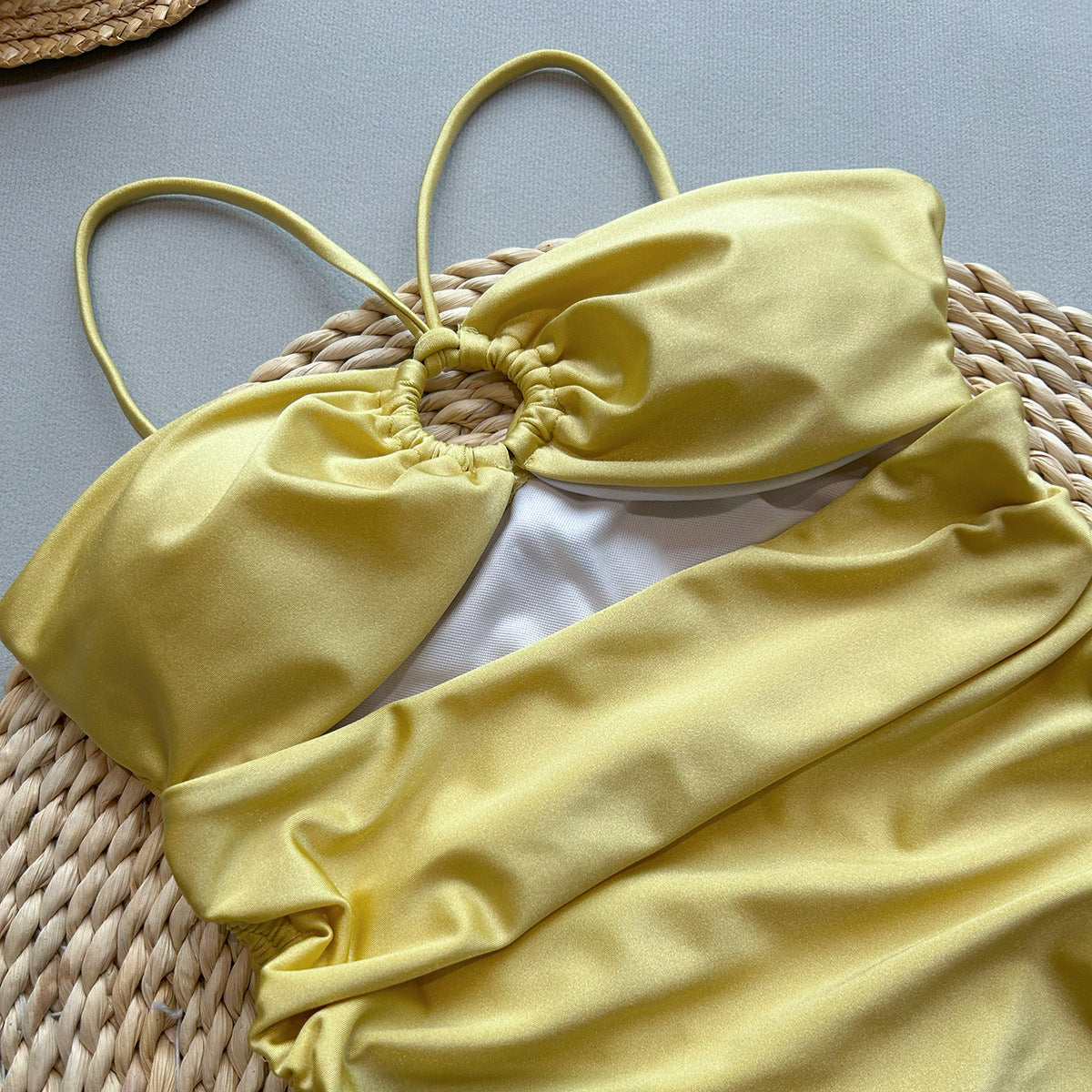 Yellow bikini set on a woven surface with a neutral background
