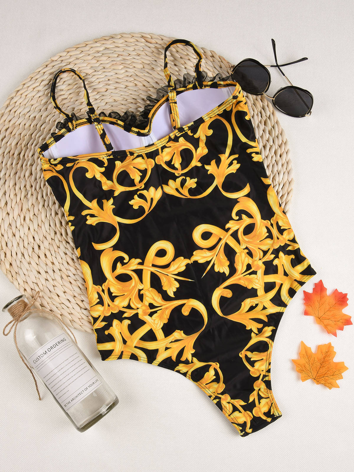 Black monokini featuring gold Brazilian‑style print, plunging neckline, side cutouts, and high‑cut leg for a bold, sculpted silhouette.