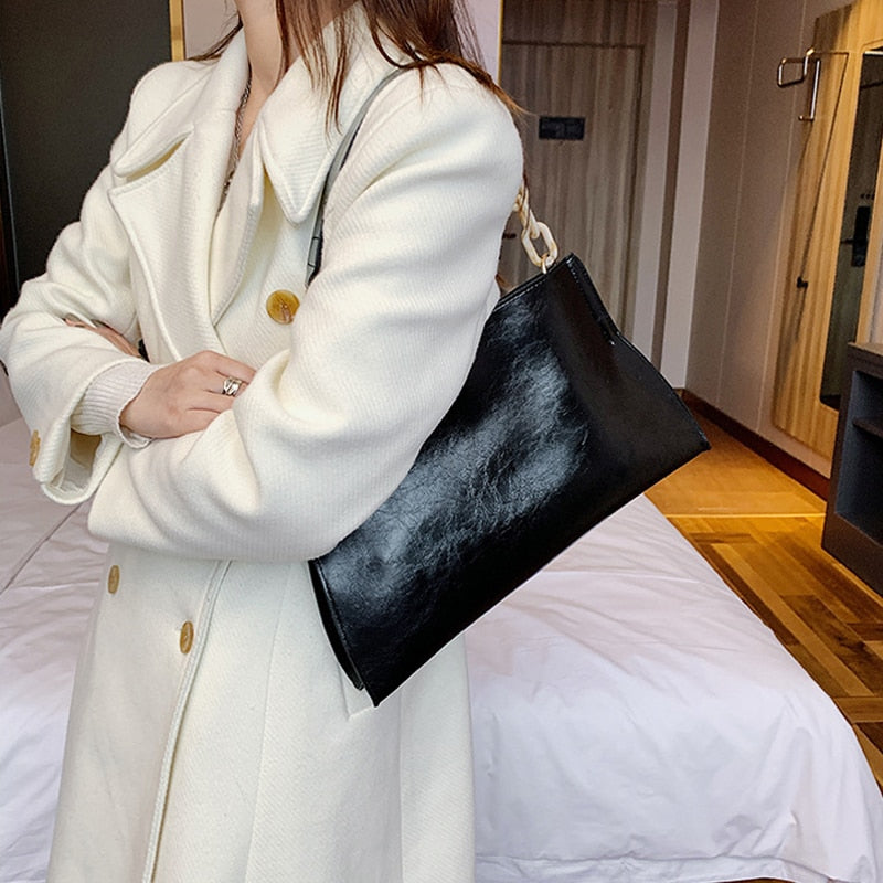 Large women's shoulder bag in soft faux leather, front view showing smooth finish and slim silhouette, black variant. Sold at PeachyBeanz.
