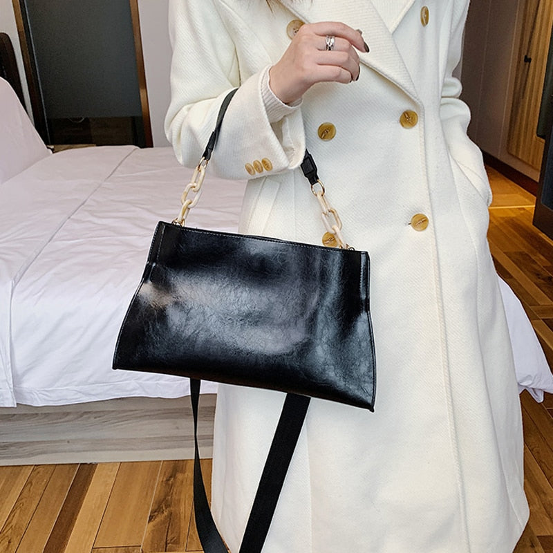 Large women's shoulder bag in soft faux leather, front view showing smooth finish and slim silhouette, black variant. Sold at PeachyBeanz.