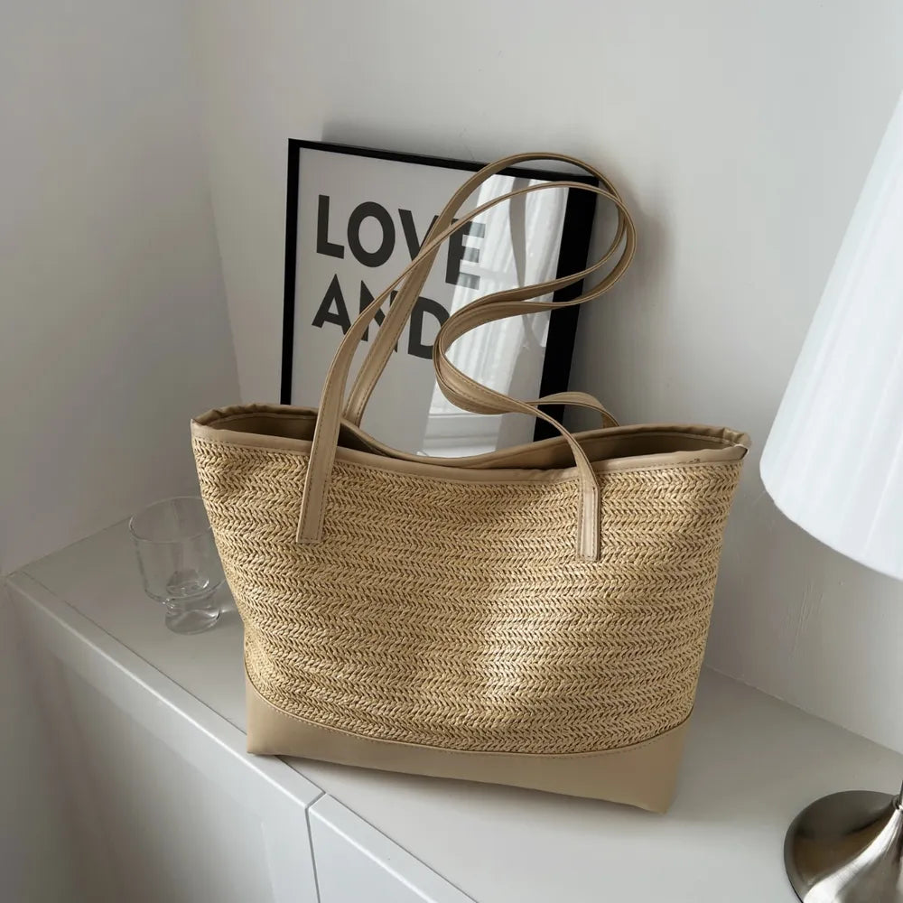 Large beige straw bag laying down on white cloth.