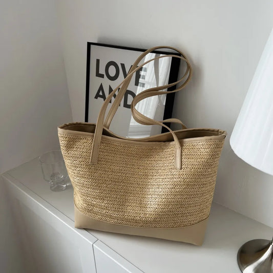Large beige straw bag laying down on white cloth.