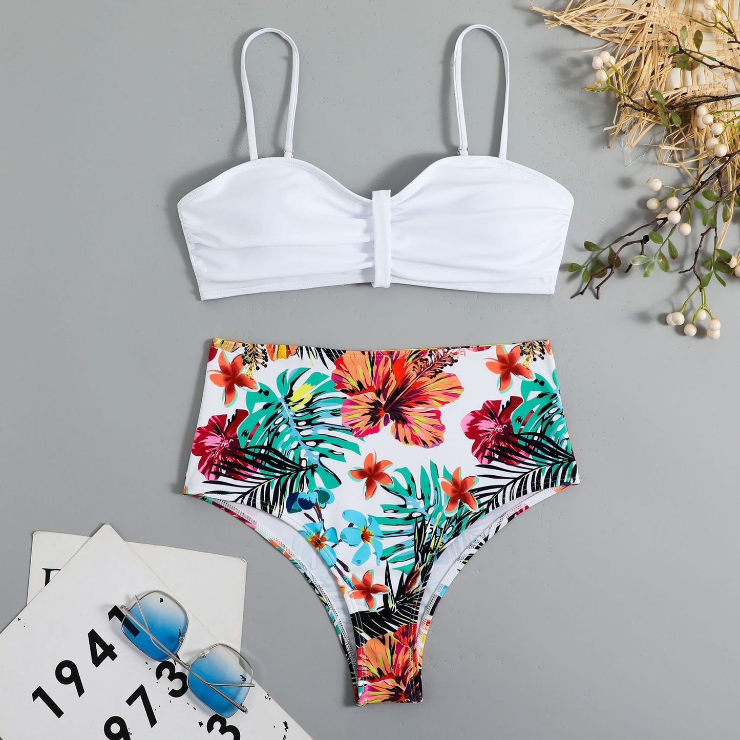 This two‑piece high‑waist bikini features a fragmented floral pattern blending bright color with a flattering, modern silhouette. 