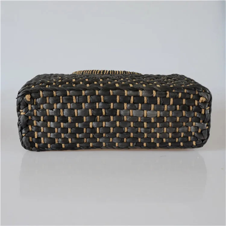 Woven clutch bag with black and gold pattern on a light gray background