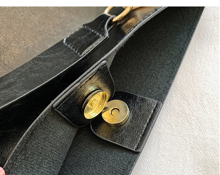 Close-up of a black leather bag with gold hardware on a neutral background