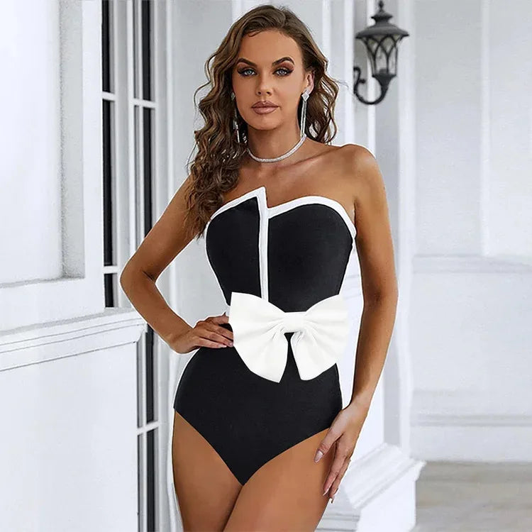 Woman wearing a black and white swimsuit with a bow detail in an elegant indoor setting.