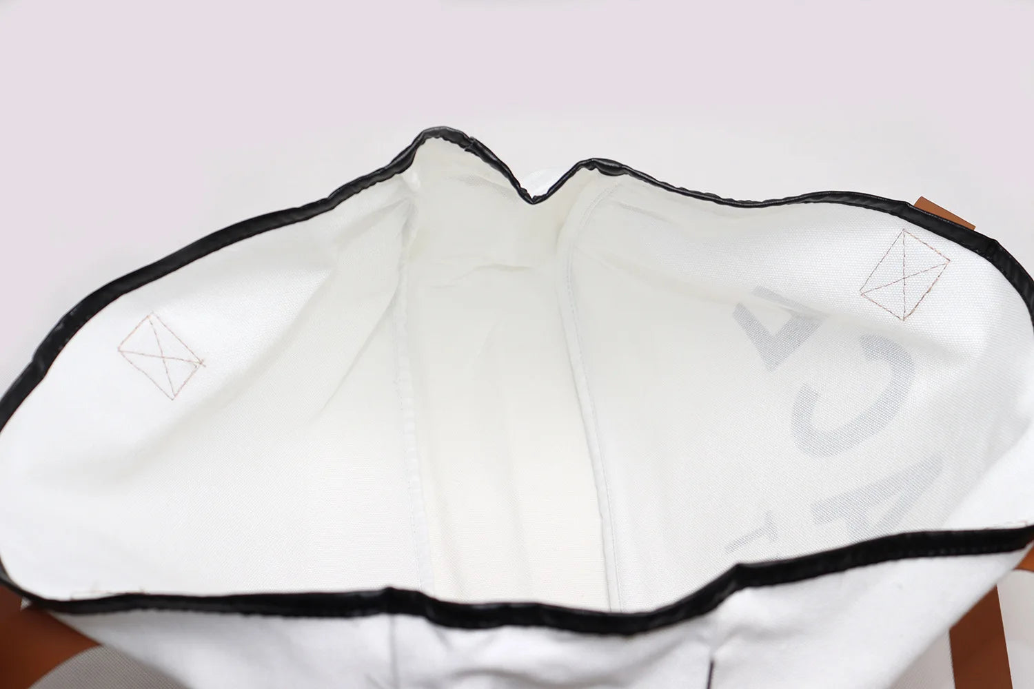 White garment bag with black trim on a light pink background