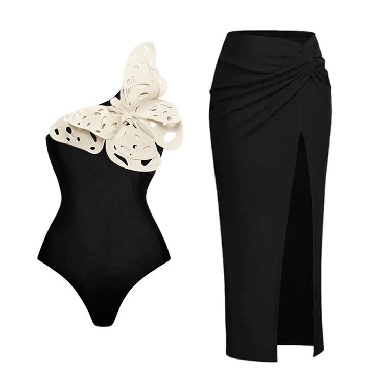 Black two‑piece swimsuit with one‑shoulder top and matching bottoms; padded cups without underwire; solid minimalist design shown on model from front.