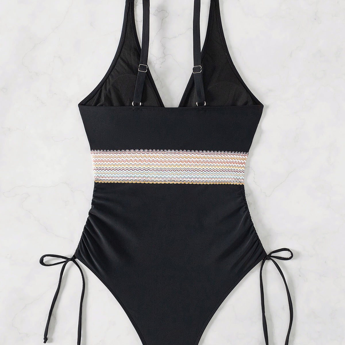 Black swimsuit with tie ups on the sides standing against a white background