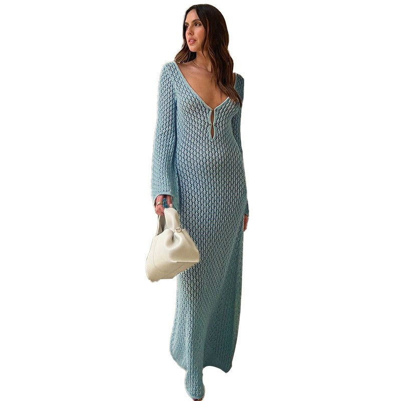 Woman in a blue textured dress standing in front of a building entrance.