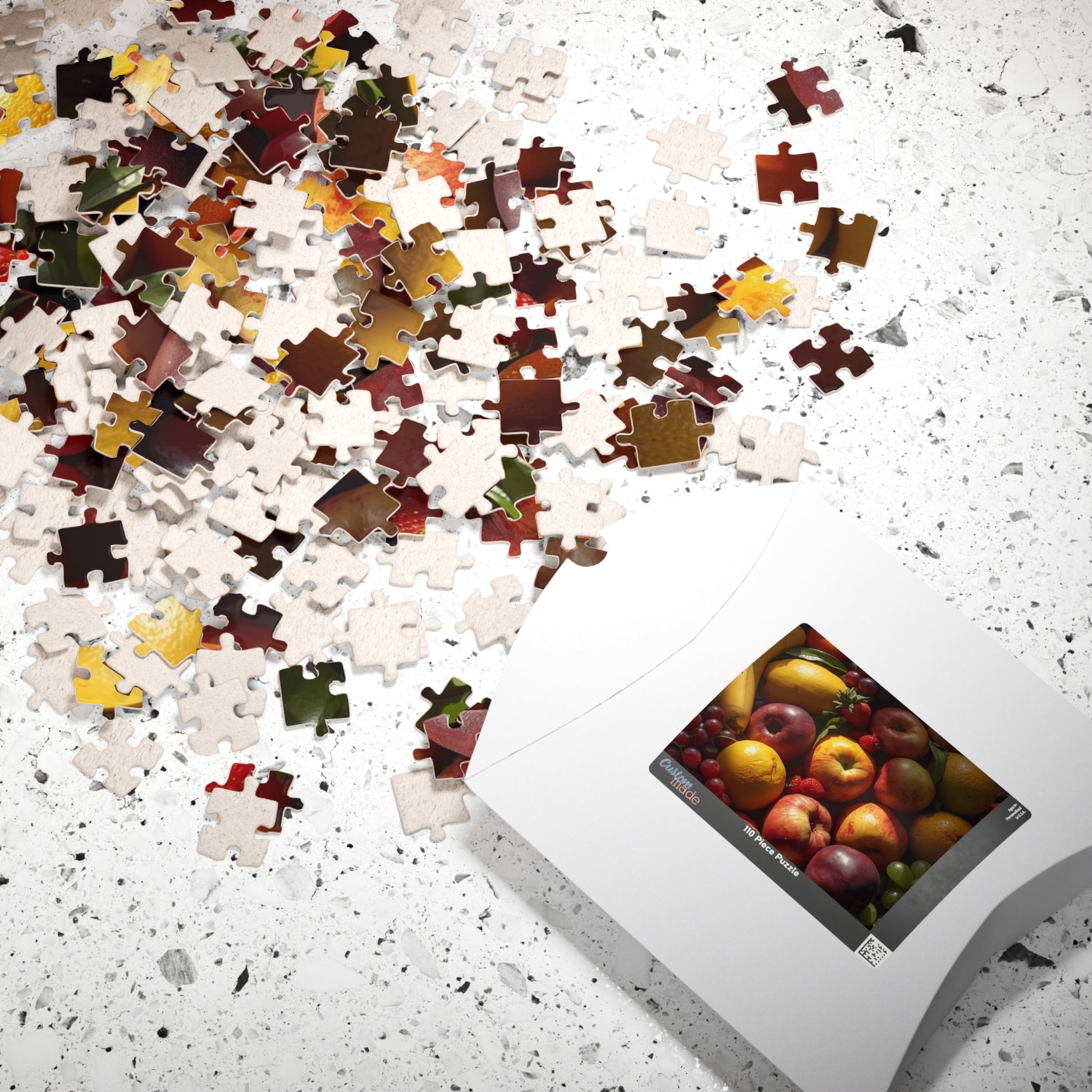 Jigsaw puzzle with completed pieces and a box of assorted fruits on a speckled surface