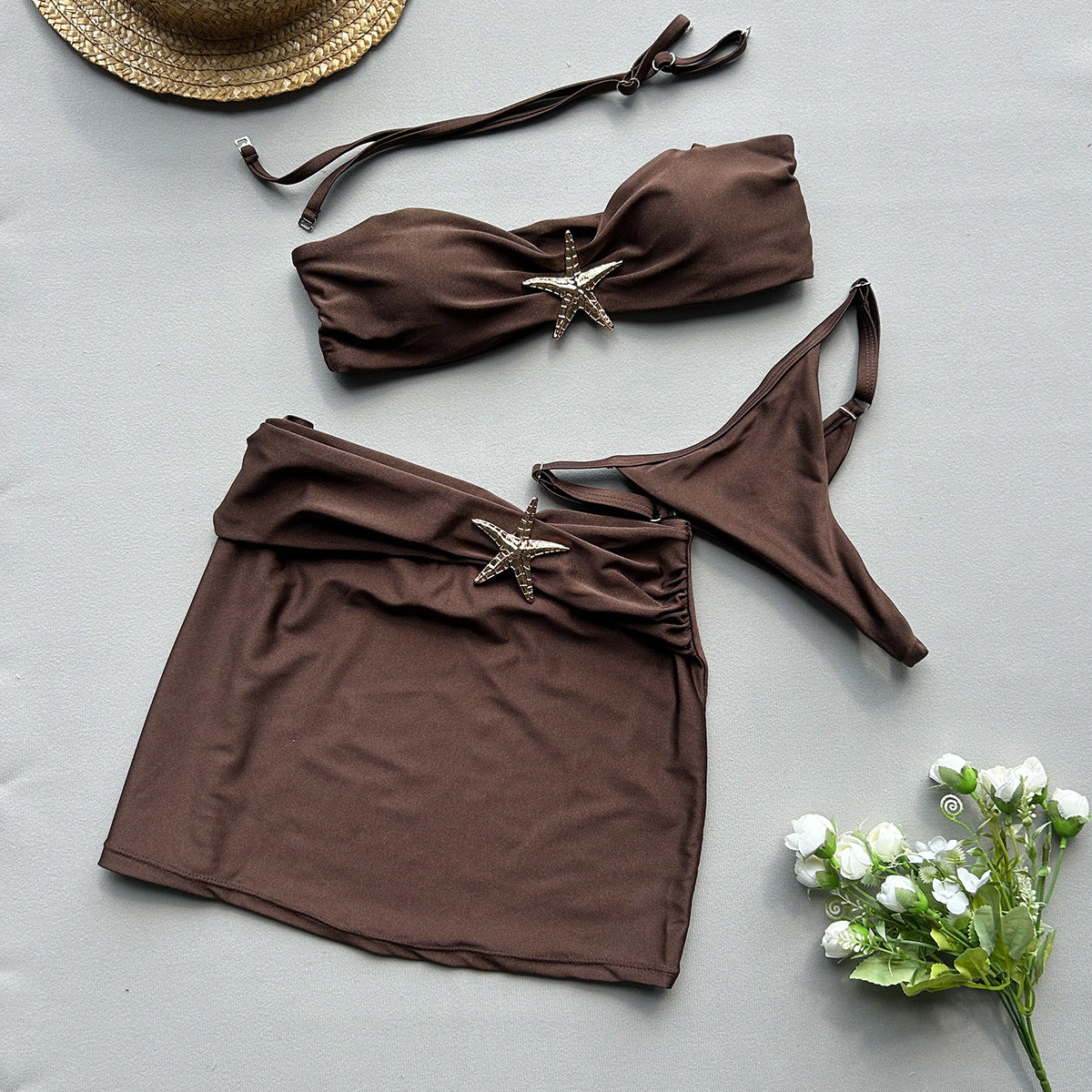 Brown bikini set with starfish decorations on a light gray 