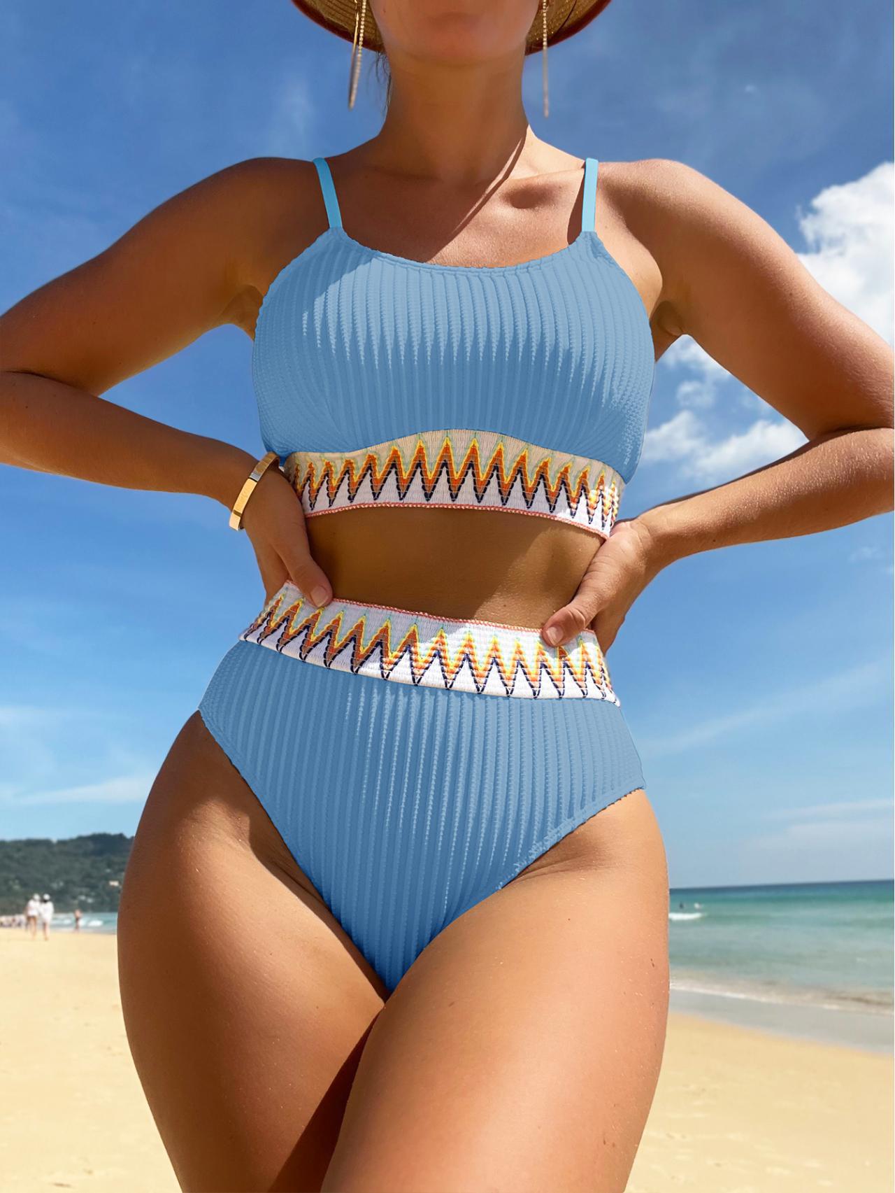 Person wearing a blue bikini with gold accents on a beach