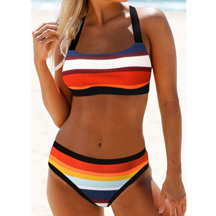 Person wearing a colorful bikini with a rainbow pattern on a beach.