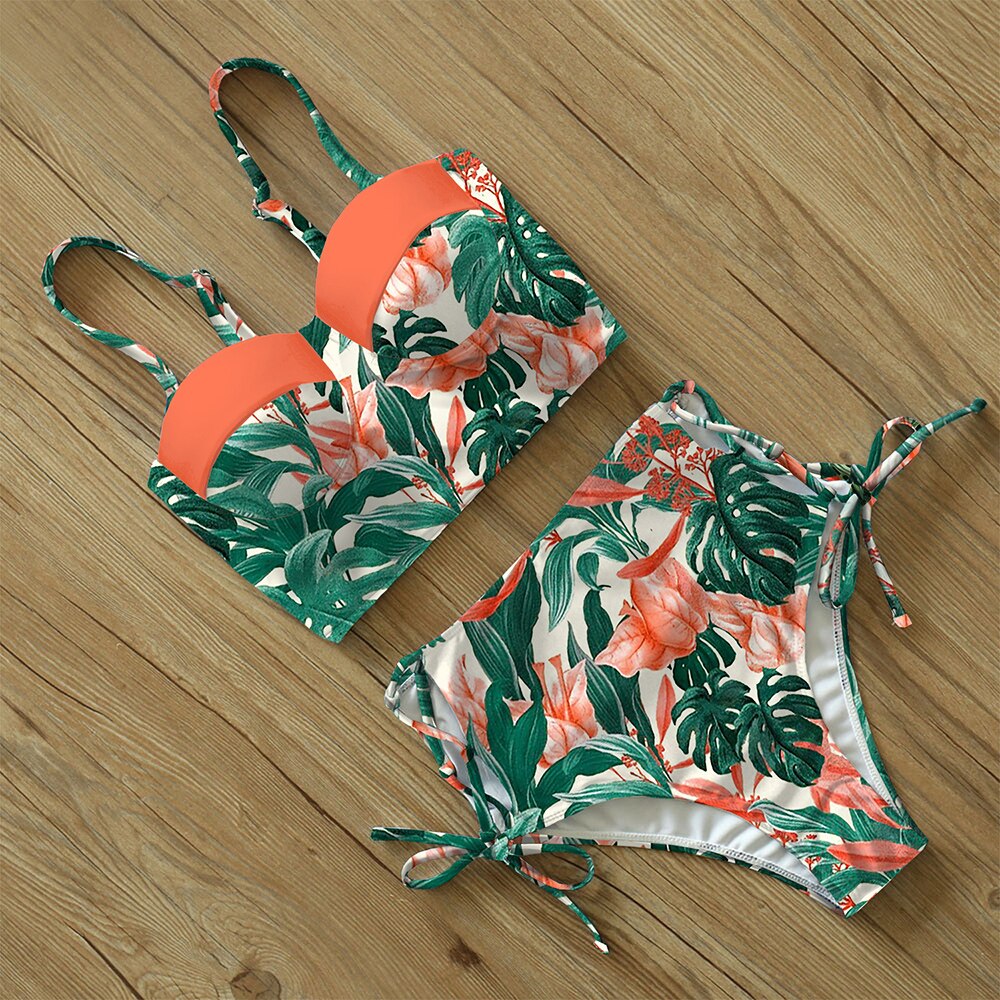 Floral swimsuit laying on a wooden floor.