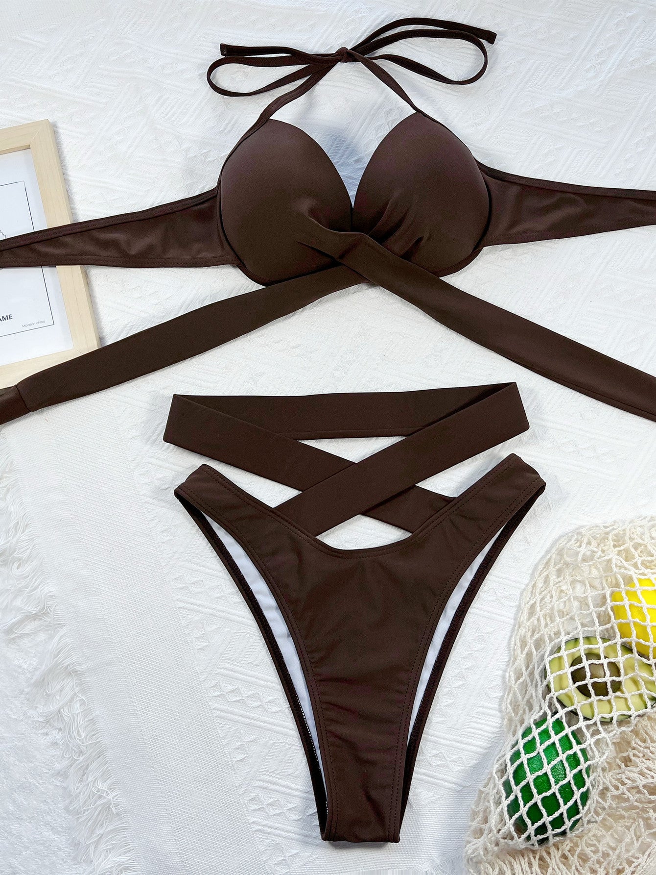 Brown bikini set on a textured surface with a bag in the background