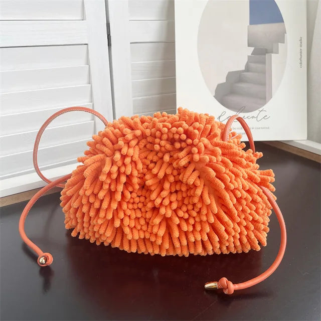 Person holding a orange textured handbag against a white wall sold at PeachyBeanz.