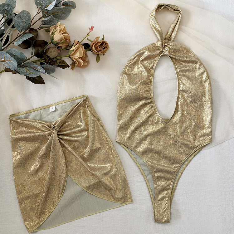Gold metallic swimsuit with open back and knot detail on a neutral background