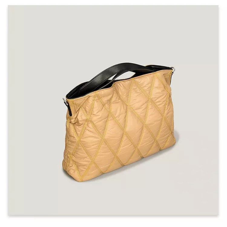 Beige quilted handbag with black handle on a light gray background