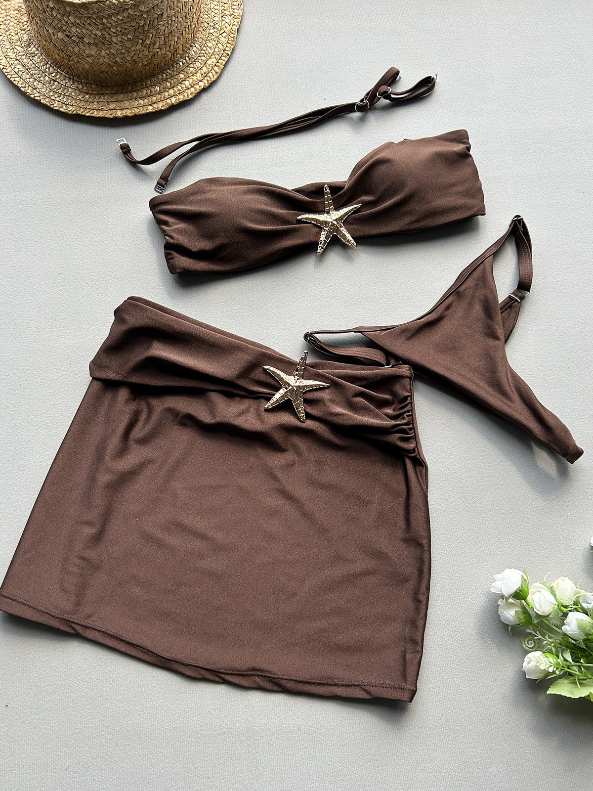 Brown bikini set with starfish decorations on a light gray 