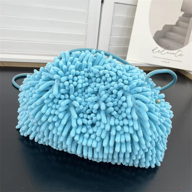 Person holding a blue textured handbag against a white wall sold at PeachyBeanz.