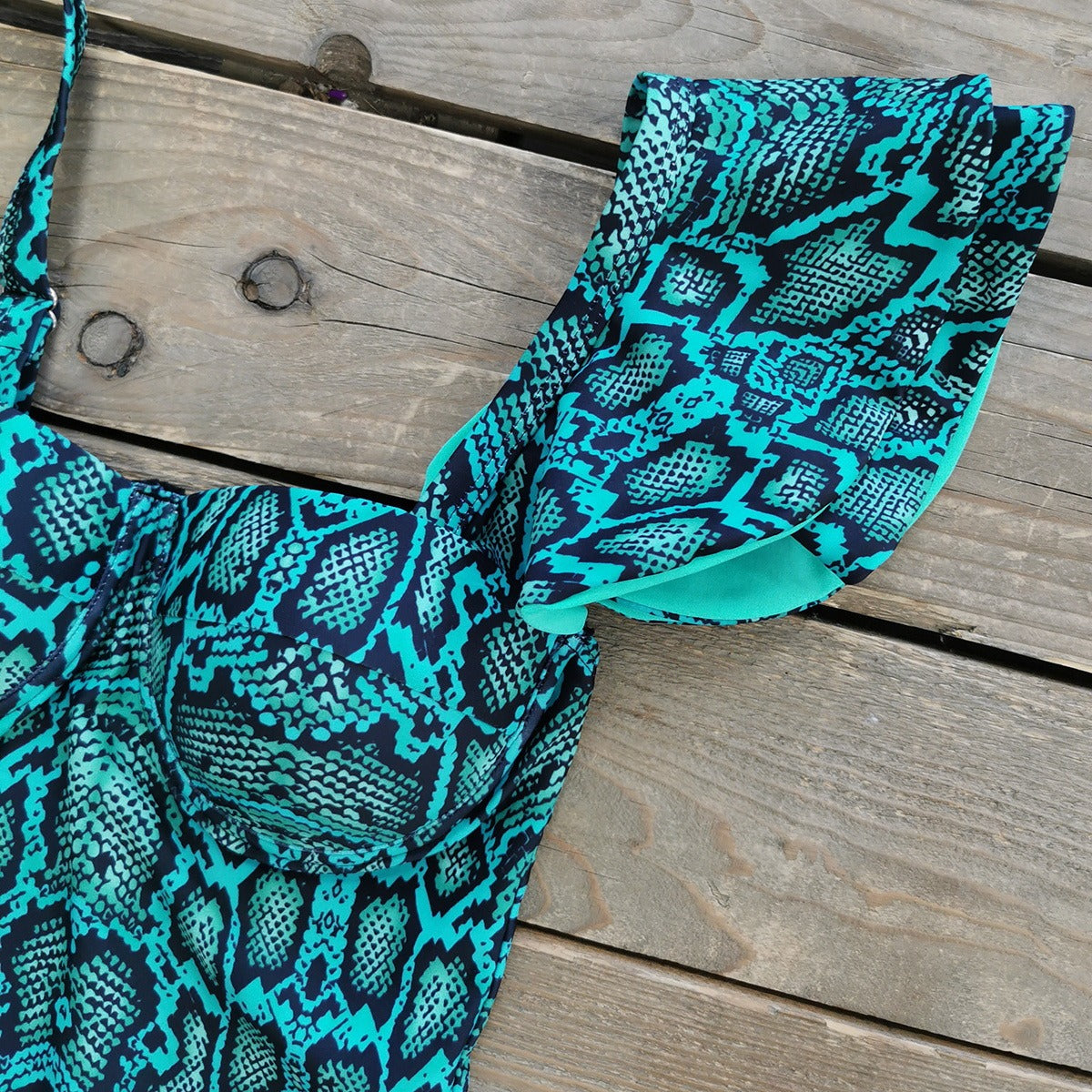 Teal and black patterned swimsuit on a wooden surface