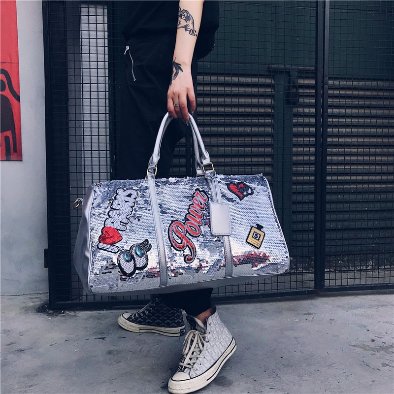 Silver sequin clutch with 'I ❤️ Parks' text against a brick wall.