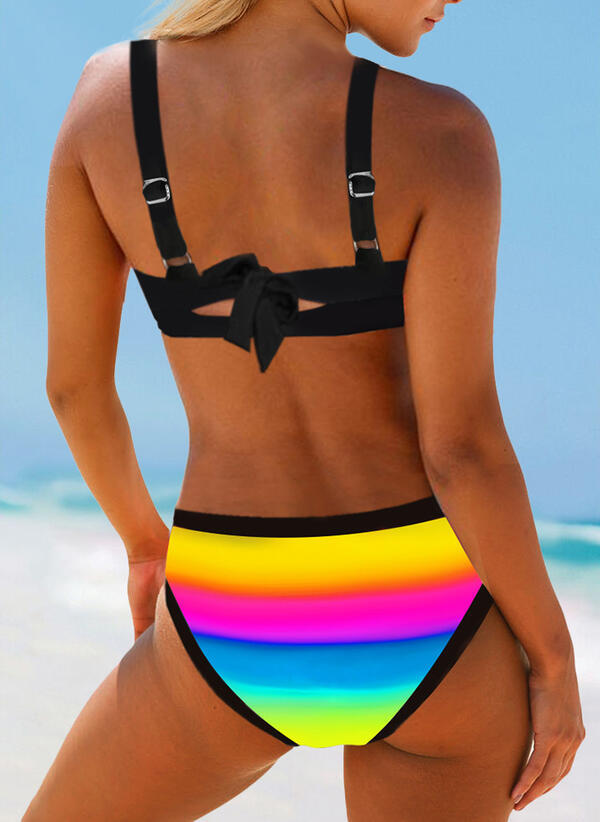 Person wearing a colorful bikini with a rainbow pattern on a beach.
