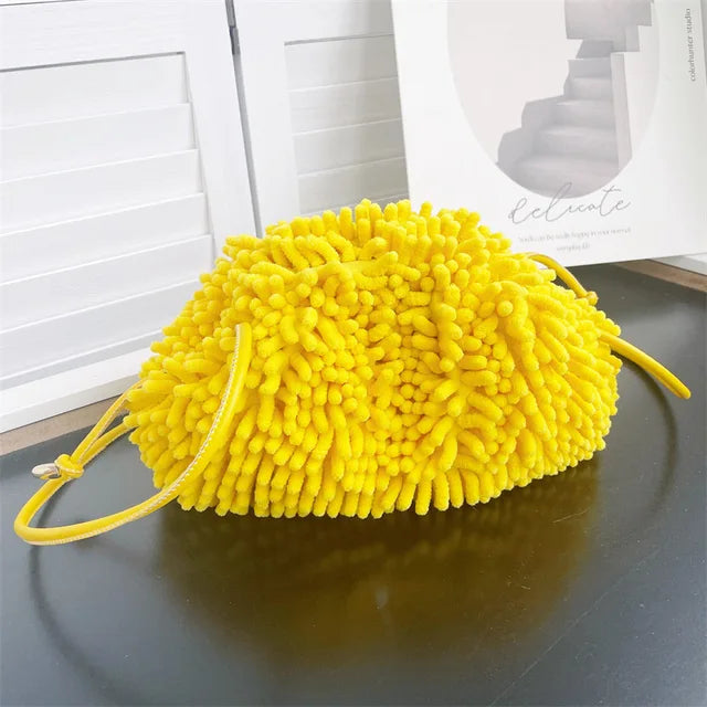 Person holding a yellow textured handbag against a white wall sold at PeachyBeanz.