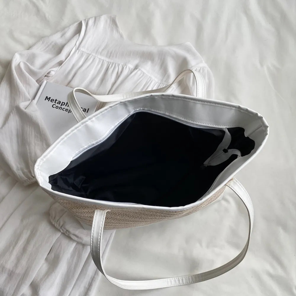 Large white straw bag laying down on white cloth.