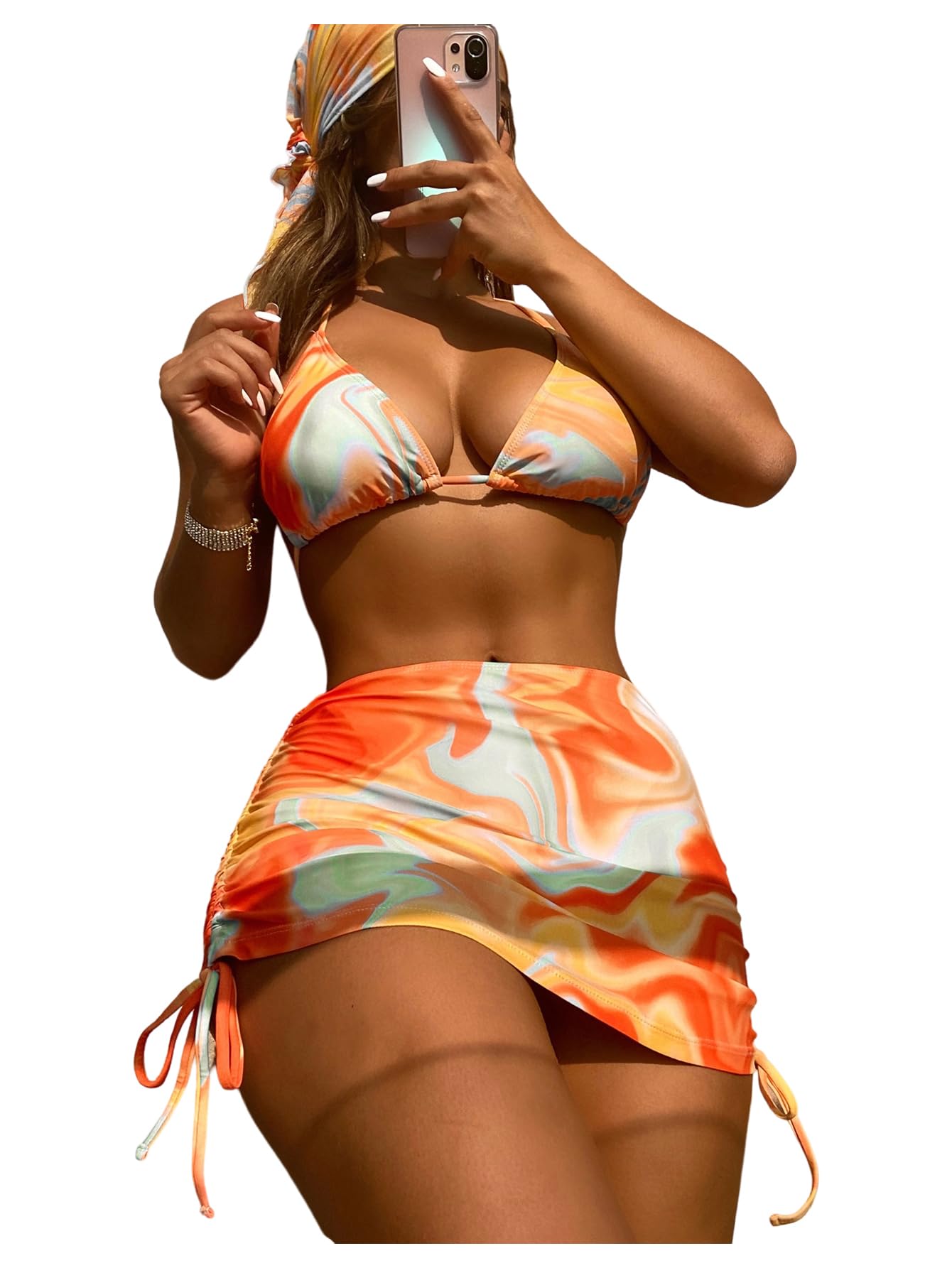 Woman taking a mirror selfie wearing an orange and white patterned bikini with a matching skirt.