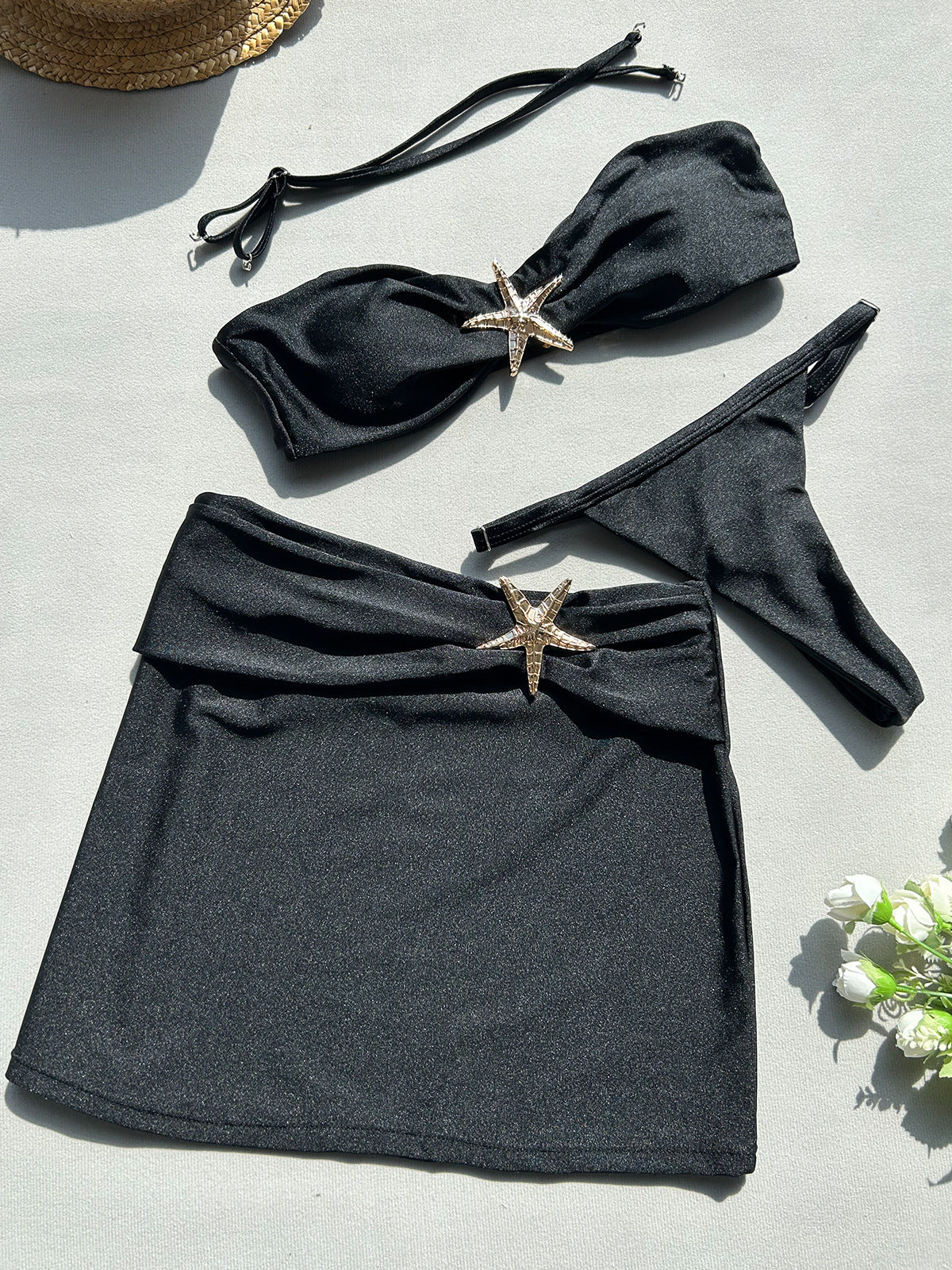 Black bikini set with starfish decorations on a light gray 