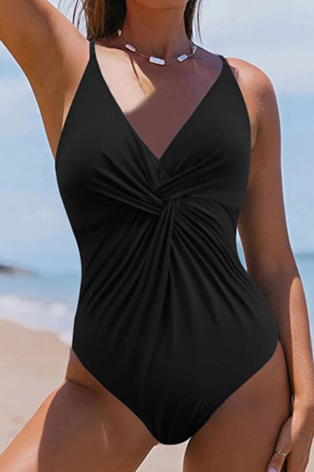 Black one‑piece swimsuit with butterfly print and crisscross V‑neck detail.
