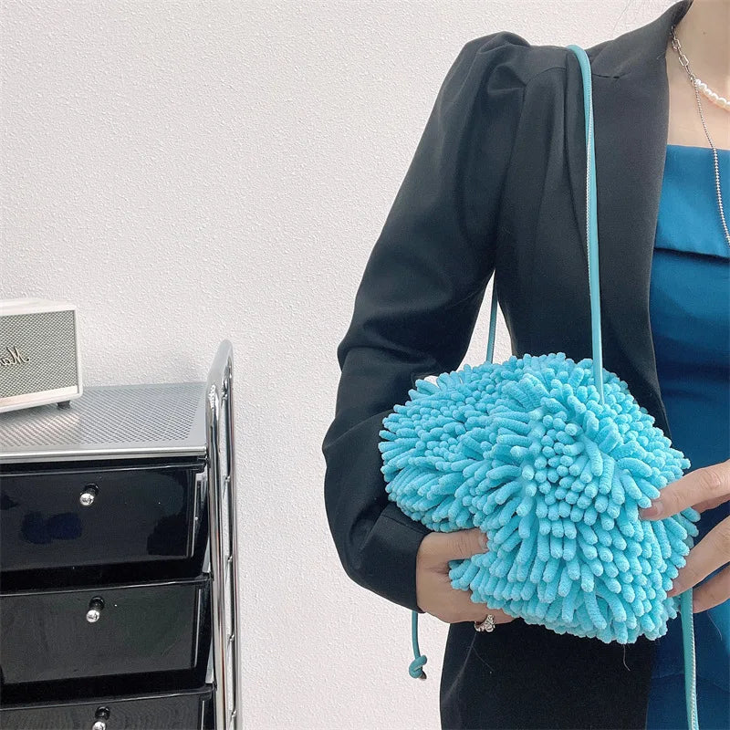 Person holding a blue textured handbag against a white wall sold at PeachyBeanz.