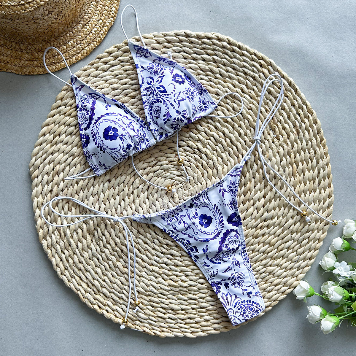 Purple printed two‑piece bikini with adjustable tie‑up straps and triangle‑style bottoms displayed on a plain background.