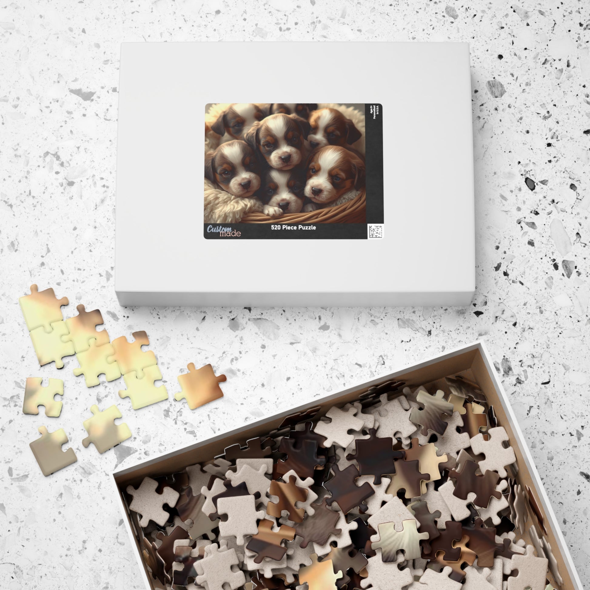 Puzzle set with a box of puzzle pieces and a box featuring puppies on a light gray surface.