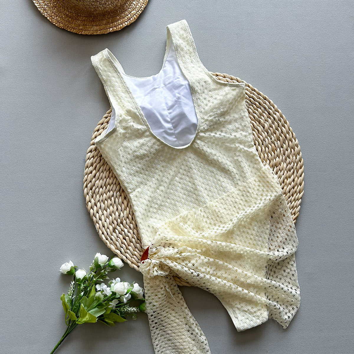 White woven swimsuit and sarong against a grey setting sold at PeachyBeanz.