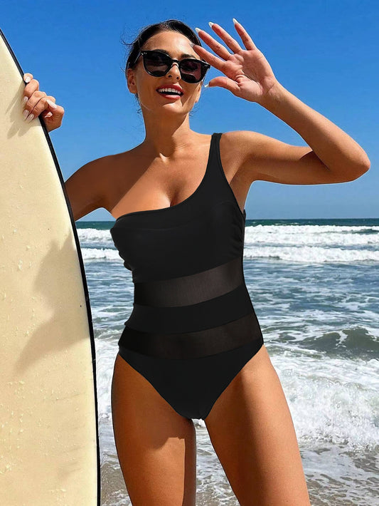 A women’s one‑piece swimsuit with a slimming mesh midsection panel, shown in a solid color with a sleek, body‑hugging silhouette. Features sleeveless design, built‑in breast pads, and a flattering, breathable fabric on a beach.