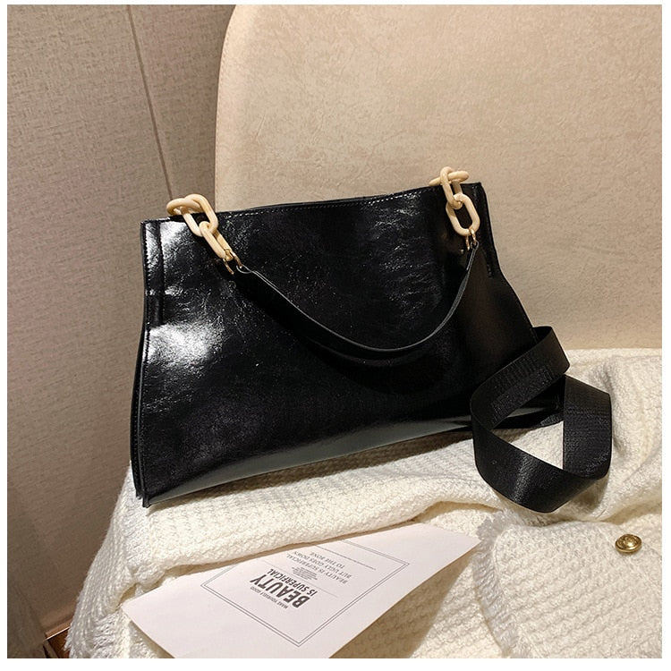 Large women's shoulder bag in soft faux leather, front view showing smooth finish and slim silhouette, black variant. Sold at PeachyBeanz.