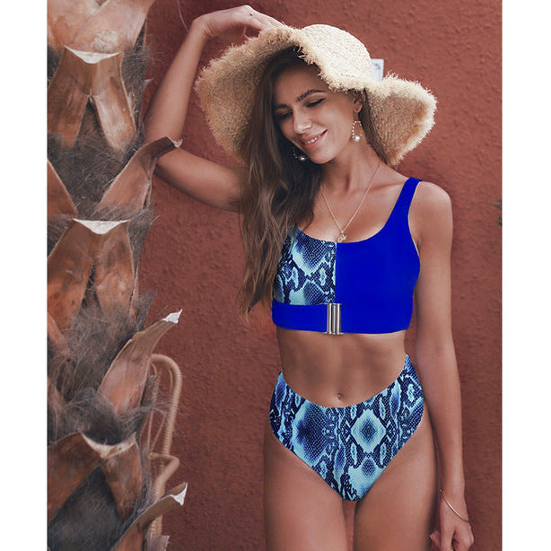 Woman wearing a blue and patterned bikini with a straw hat against a textured wall sold at PeachyBeanz.