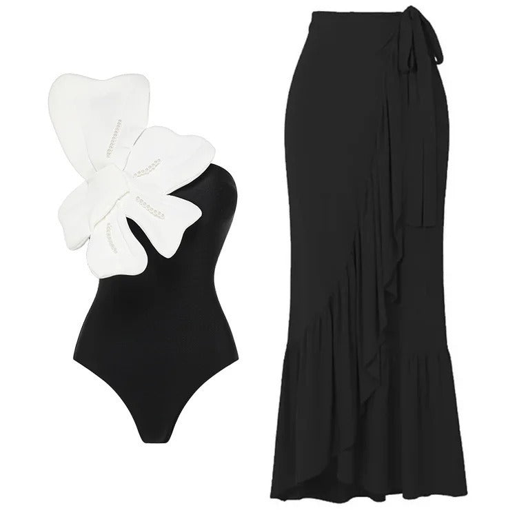 Black two‑piece swimsuit with one‑shoulder top and matching bottoms; padded cups without underwire; solid minimalist design shown on model from front.