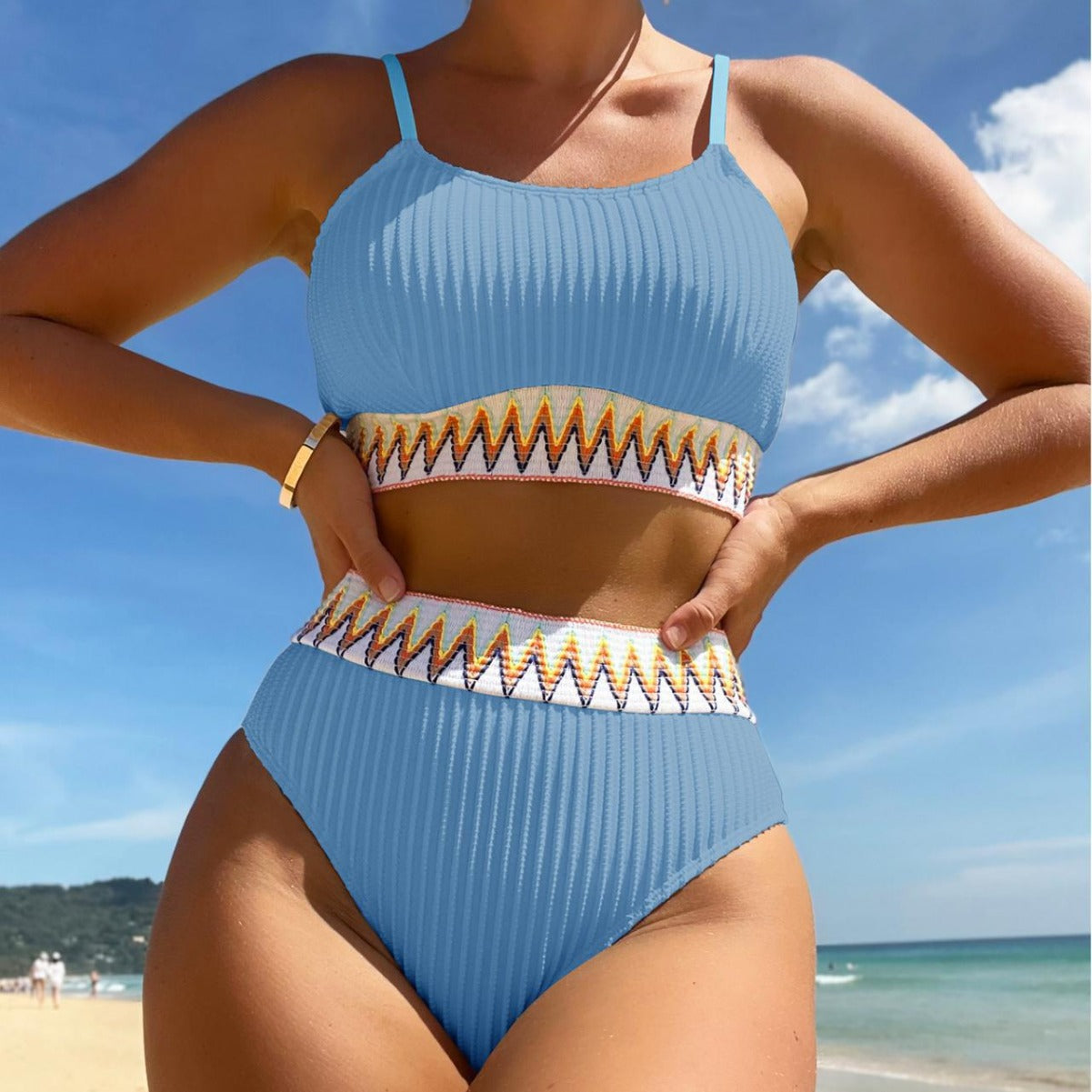 Person wearing a blue bikini with gold accents on a beach
