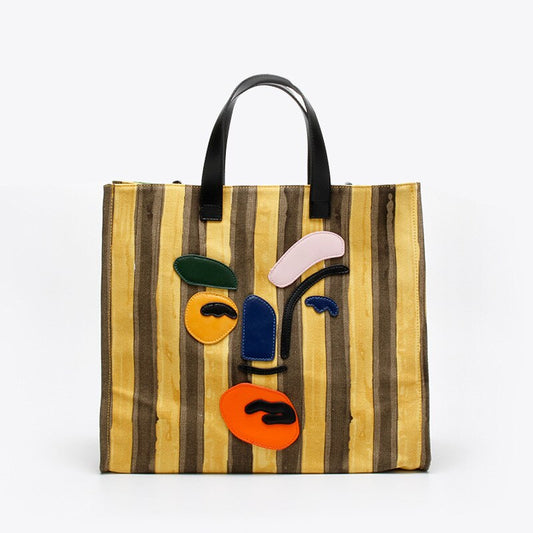 Large yellow striped canvas tote with polyester cotton lining. Modern faceless print, reinforced handles, perfect for beach days and everyday errands.