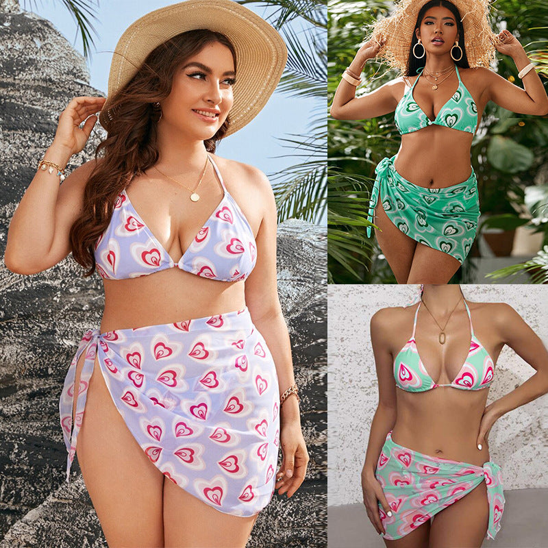Woman wearing a heart-patterned bikini set with a textured wall and palm leaves in the background sold at PeachyBeanz.