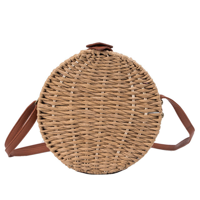 Woven handbag with leather straps on a white background