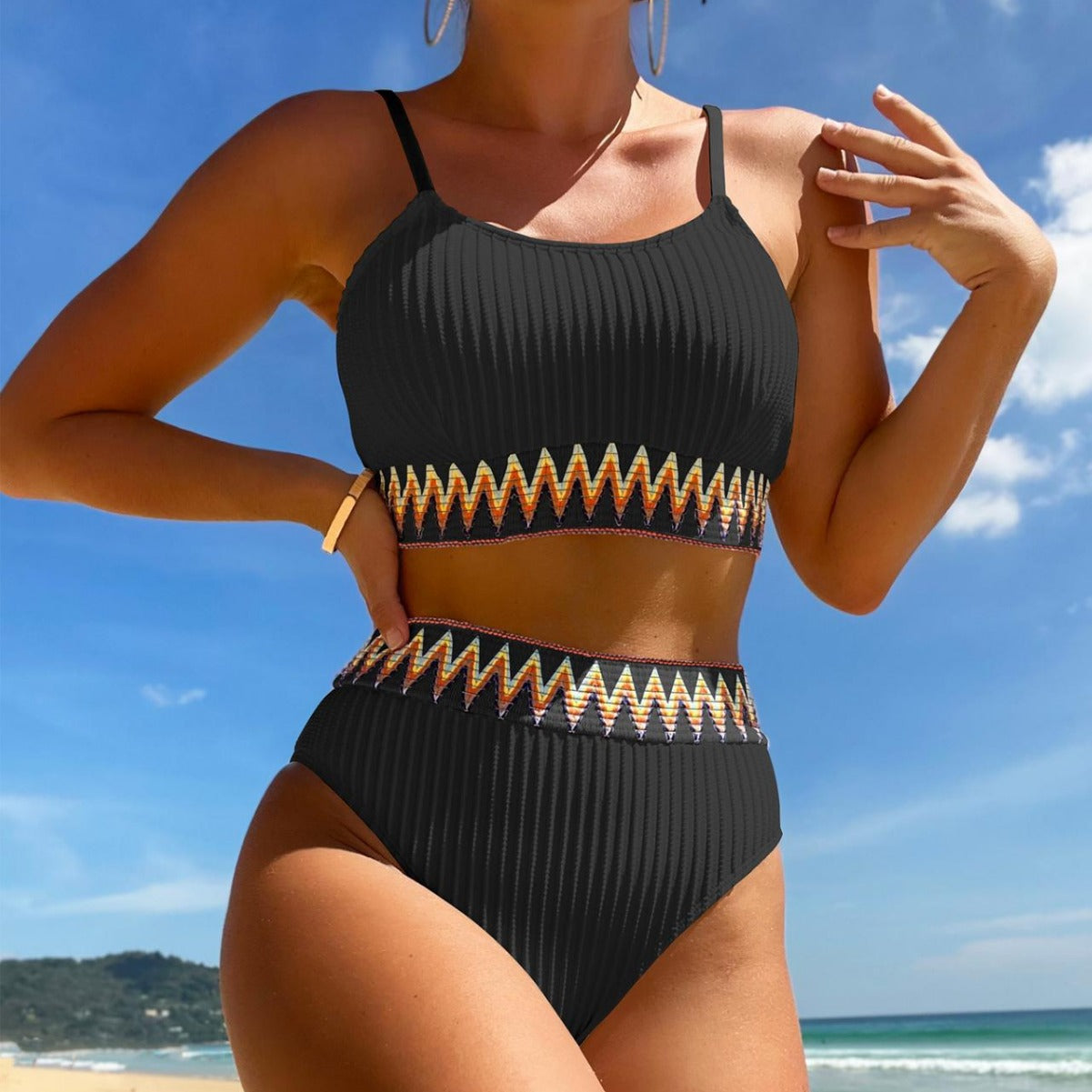 Person wearing a black bikini with gold accents on a beach