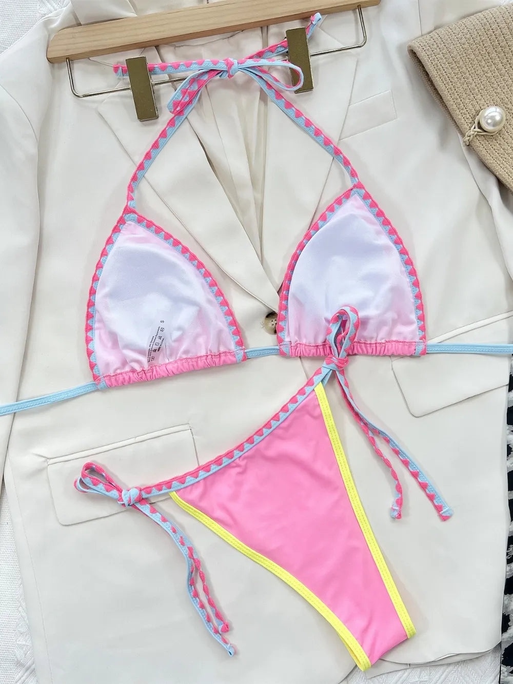 Pink swimsuit on a hanger in a white background.